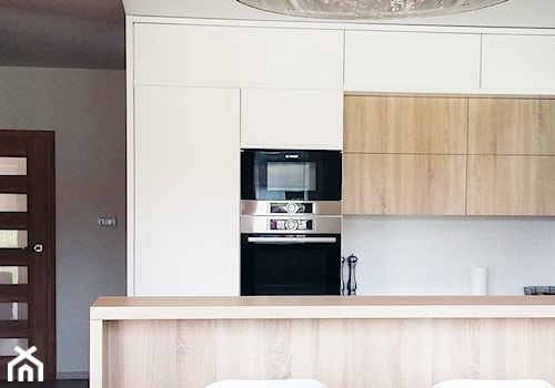 Biała kuchnia z drewnem - Średnia z salonem biała z zabudowaną lodówką kuchnia dwurzędowa, styl nowoczesny - zdjęcie od Biuro projektowe "Patio" Ewa Szymczak
