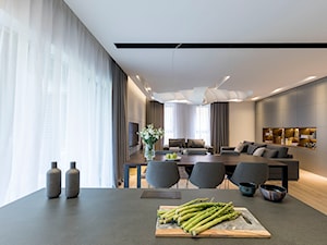Apartament z czarną kuchnią. - Duży szary salon z kuchnią z jadalnią, styl minimalistyczny - zdjęcie od Banach Architekci