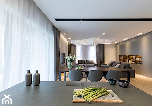 Apartament z czarną kuchnią. - Duży szary salon z kuchnią z jadalnią, styl minimalistyczny - zdjęcie od Banach Architekci