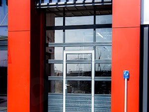 Brama segmentowa przemysłowa z przeszkleniem i drzwiami - zdjęcie od OLBUD OGRODZENIA BRAMY DRZWI I OKNA STRASZYN