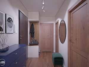 Przedpokój w stonowanych kolorach, drewniane drzwi oraz podłoga, granatowa szafka, szafa z siedziski ... - zdjęcie od VISO Pracownia Projektowa