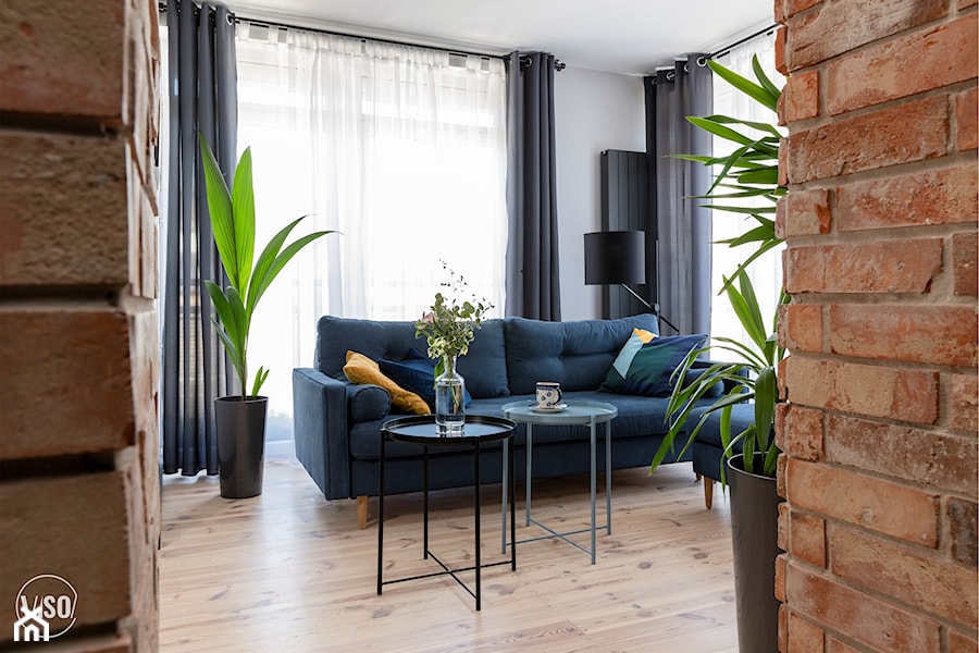 Salon z granatową kanapą i elementami dekoracyjnymi z cegły - zdjęcie od VISO Pracownia Projektowa