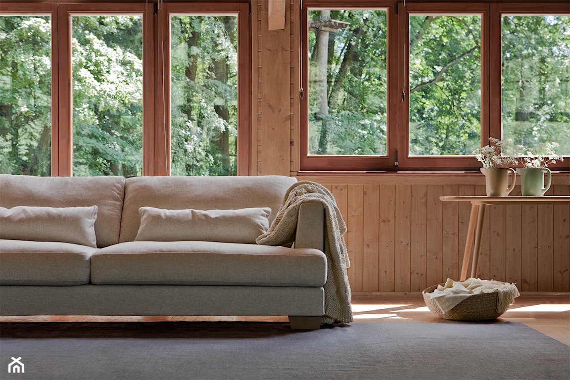 szary dywan, beżowa sofa SITS, drewniane ściany, beżowa narzuta