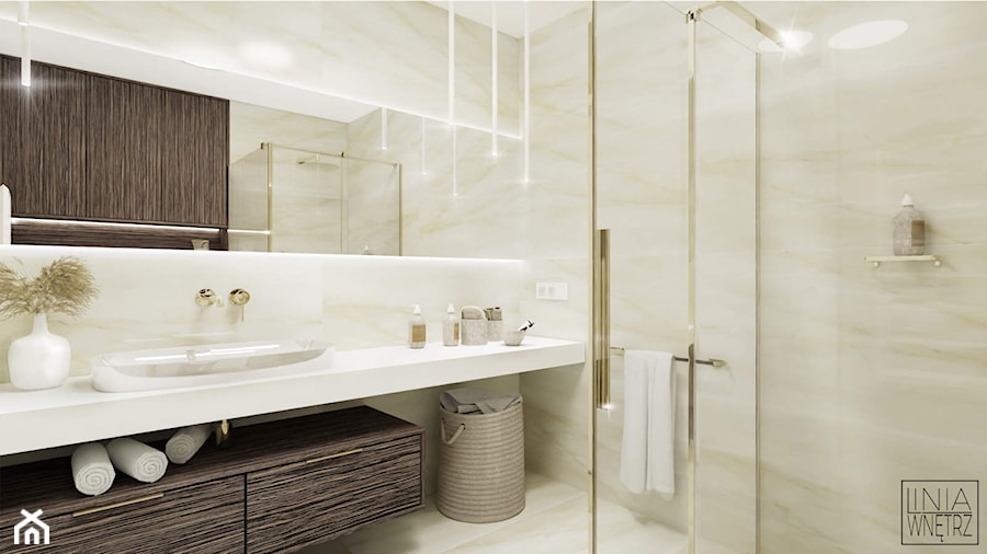 Projekt jasnej małej łazienki ze złotymi dodatkami w domu jednorodzinnym z dużym podświetlanym lustrem i dużym blatem pod umywalką - zdjęcie od LINIA WNĘTRZ - PROJEKTOWANIE WNĘTRZ DOMÓW I MIESZKAŃ
