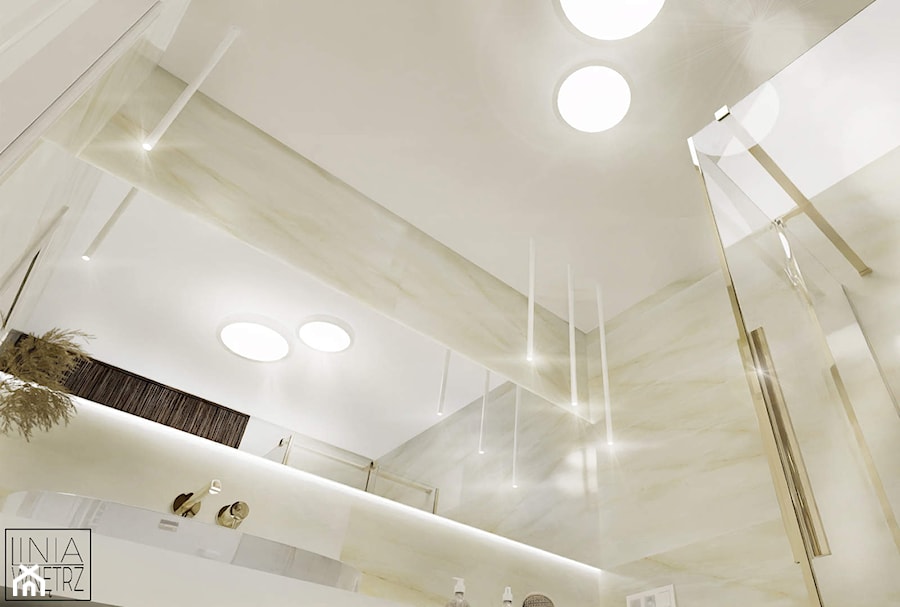 Projekt jasnej małej łazienki ze złotymi dodatkami w domu jednorodzinnym z dużym podświetlanym lustrem i dużym blatem pod umywalką - zdjęcie od LINIA WNĘTRZ - PROJEKTOWANIE WNĘTRZ DOMÓW I MIESZKAŃ