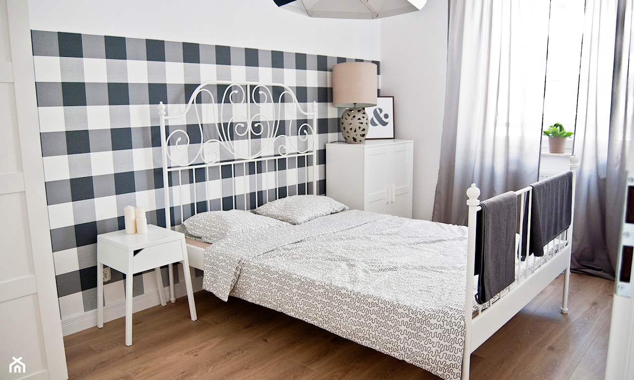 tapeta w biało-czarną kratę w sypialni, łóżko z metalową ramą, drewniana podłoga