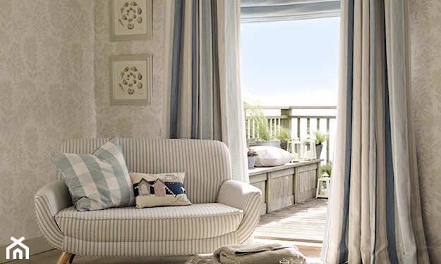 błękitne zasłony do podłogi, lampa wisząca z wiklinowym abażurem, sofa w biało-błękitne paseczki