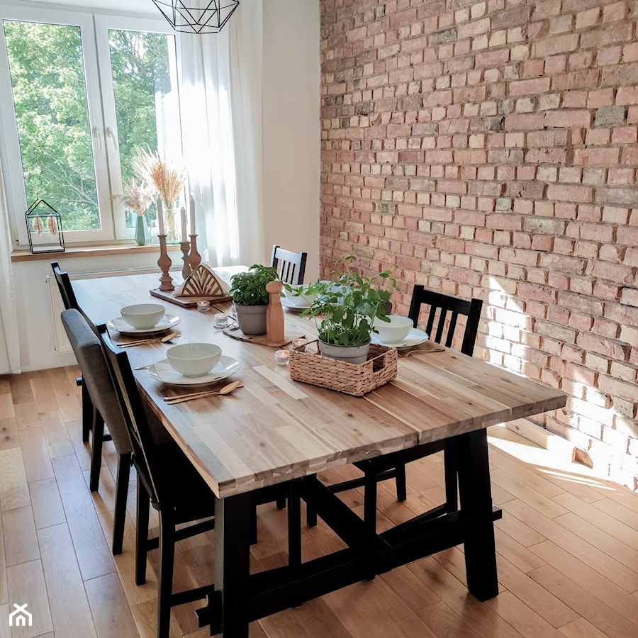 Jadalnia z dużym, drewnianym stołem i ceglaną ścianą. - zdjęcie od Knapik Design
