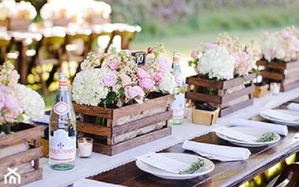 stół w ogrodzie, biała zastawa, drewniane skrzynki ze  świeżymi kwiatami