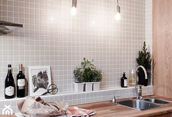 beżowa mozaika na ścianie w kuchni, drewniany blat kuchenny, białe doniczki ze świeżymi ziołami