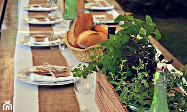 drewniany stół w ogrodzie, skrzynia z ziołami, biała zastawa