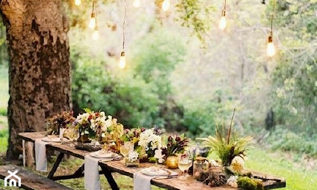 drewniany stół w ogrodzie, drewniane ławki, lampki żarówki na kablach