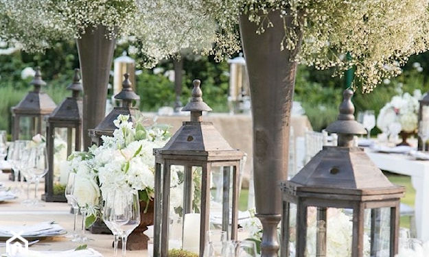 stół w ogrodzie, metalowe lampiony, szary wazon ze świeżymi kwiatami
