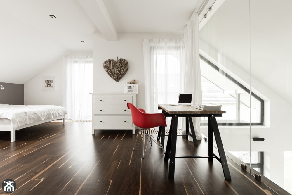 sypialnia na poddaszu, podłoga z ciemnego drewna, białe ściany, czerwony fotel, drewniane biurko