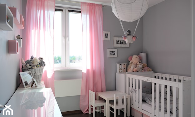 różowe zasłony, szare ściany w pokoju dziecka, biały stolik dziecięcy, białe łóżeczko dziecięce