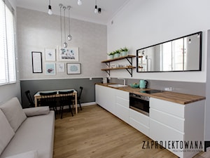 Apartament w stylu skandynawskim - Mała otwarta z salonem biała szara z zabudowaną lodówką z podblatowym zlewozmywakiem kuchnia jednorzędowa z oknem, styl skandynawski - zdjęcie od ZAPROJEKTOWANA