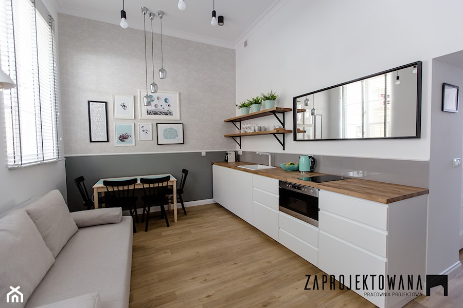 Apartament w stylu skandynawskim - Mała otwarta z salonem biała szara z zabudowaną lodówką z podblatowym zlewozmywakiem kuchnia jednorzędowa z oknem, styl skandynawski - zdjęcie od ZAPROJEKTOWANA