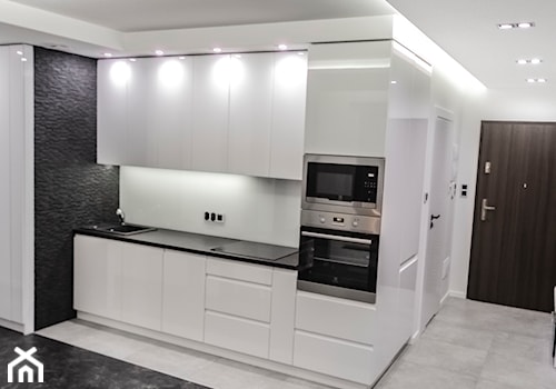 Mała z salonem biała czarna z zabudowaną lodówką z podblatowym zlewozmywakiem kuchnia jednorzędowa, styl minimalistyczny - zdjęcie od Maldekor Mariusz Gąsiorowski