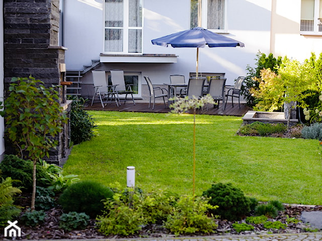 ogród z tarasem i niebieskim parasolem