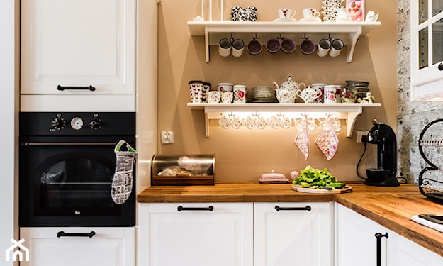 białe szafki kuchenne z drewnianym blatem, podświetlana półka w kuchni, ozdobne filiżanki
