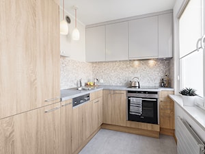 Mieszkanie w Kołobrzegu - Średnia z salonem biała z zabudowaną lodówką kuchnia w kształcie litery l z marmurem nad blatem kuchennym, styl nowoczesny - zdjęcie od PracowniaPolka