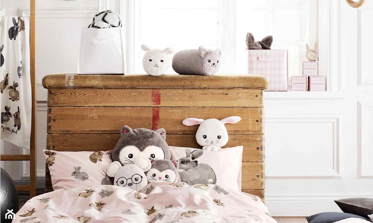 łóżko dziecięce z drewnianym zagłówkiem, pościel w króliki, różowe pudełka