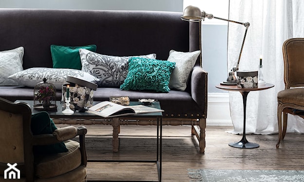 metalowa lampka pix, szara sofa, drewniana podłoga, zielone poduszki we wzory florystyczne