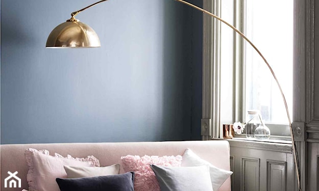 niebieska ściana, złota lampa, różowa sofa, biała poduszka, grafitowa poduszka