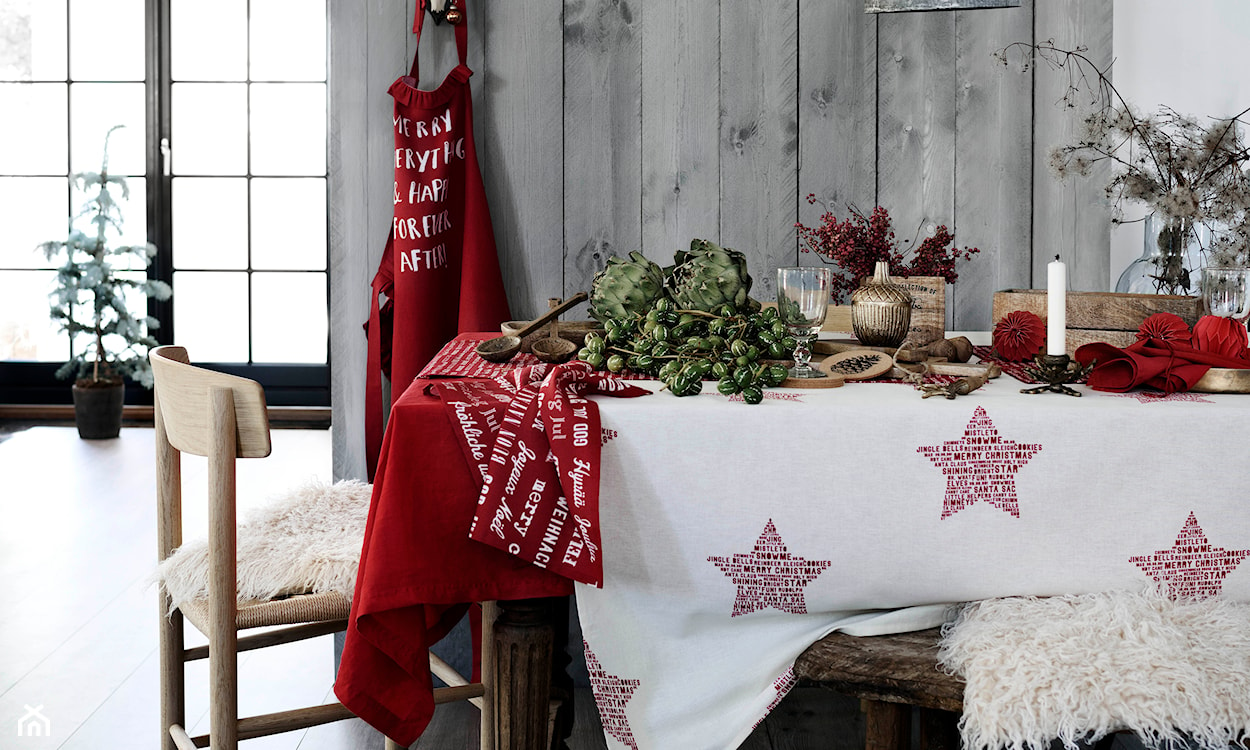 świąteczny obrus w czerwone gwiazdki, drewniane krzesło, biała narzuta z długim włosiem, szara ściana z paneli