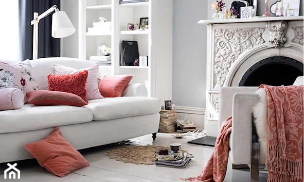 biała sofa, czerwone poduszki, biała lampa stojąca, biały kominek ze zdobieniami