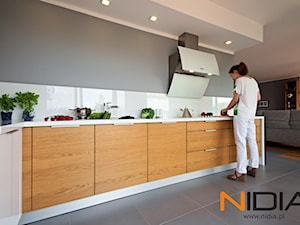 Apartament w Opolu (2011r) - Duża otwarta z salonem szara z zabudowaną lodówką kuchnia w kształcie litery l z kompozytem na ścianie nad blatem kuchennym, styl minimalistyczny - zdjęcie od NIDIA