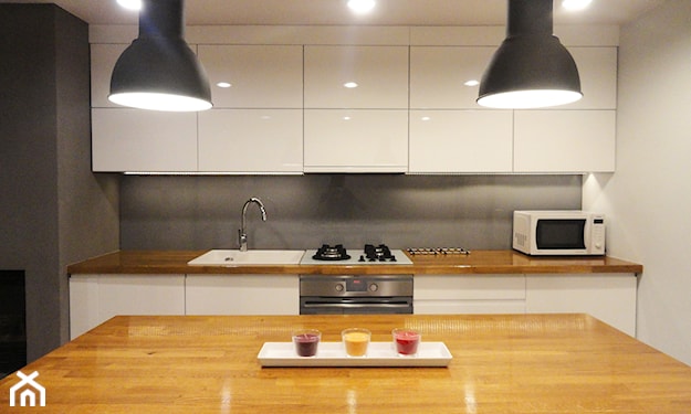 białe meble kuchenne z drewnianym blatem, szara lampa wisząca, szare ściany w kuchni, kuchnia w stylu skandynawskim