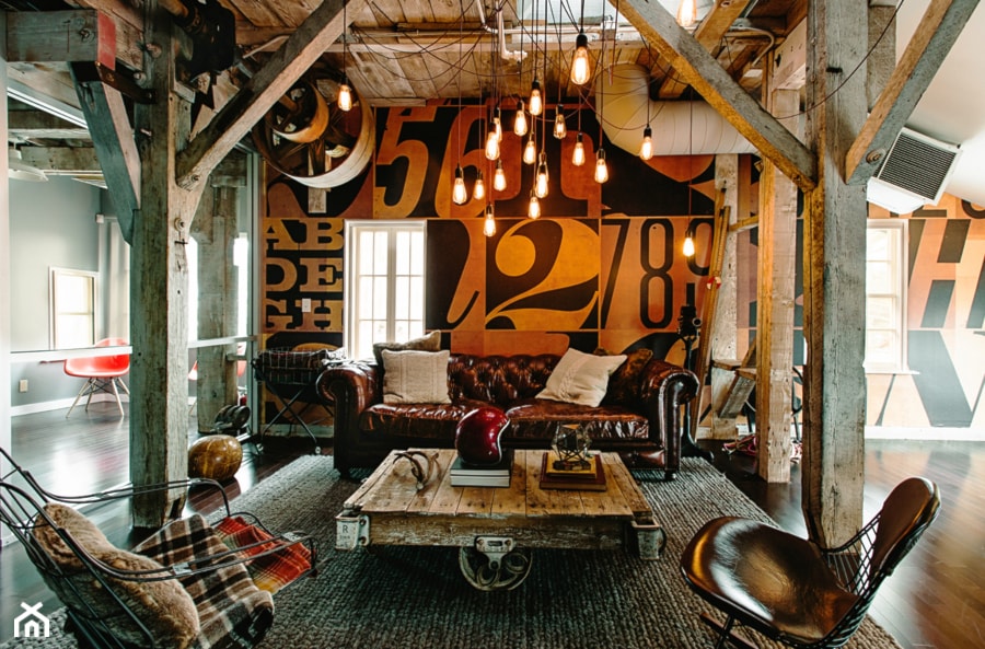 drewniany strop, lampy wiszące żarówki, skórzana sofa, metalowy fotel, drewniana podłoga