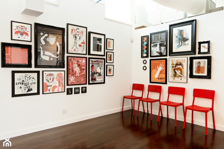 czerwone krzesła, białe ściany, kolorowe grafiki na ścianach w czarnych ramach
