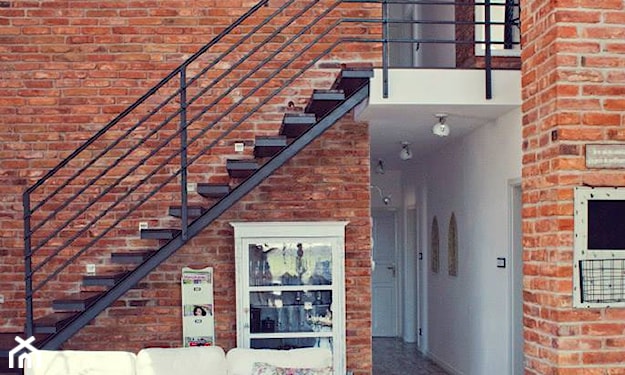 ceglana ściana, metalowe schody, kremowa sofa