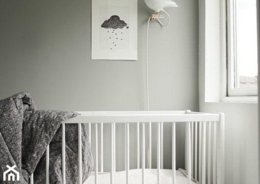 szare ściany w pokoju dziecka, szara narzuta, białe łóżeczko dziecięce, ozdobny ptak nad łóżeczkiem