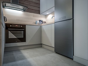 Kuchnia w dwóch odsłonach - Mała otwarta z salonem biała z zabudowaną lodówką kuchnia w kształcie litery u, styl skandynawski - zdjęcie od wizjaprzestrzeni.pl
