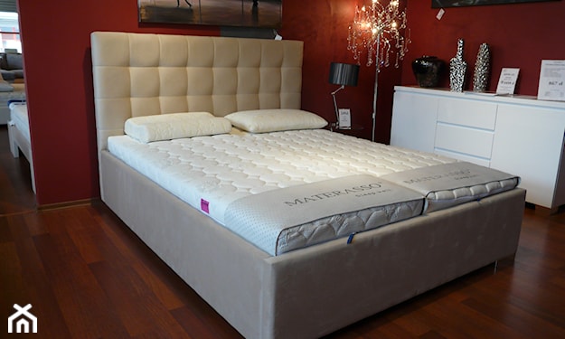 beżowe łóżko z pikowanym zagłówkiem, biała komoda, bordowa ściana
