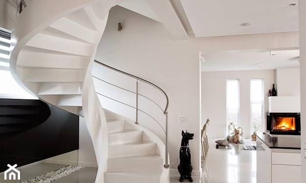 biała kamienna podłoga, białe spiralne schody, metalowa balustrada, kominek w salonie