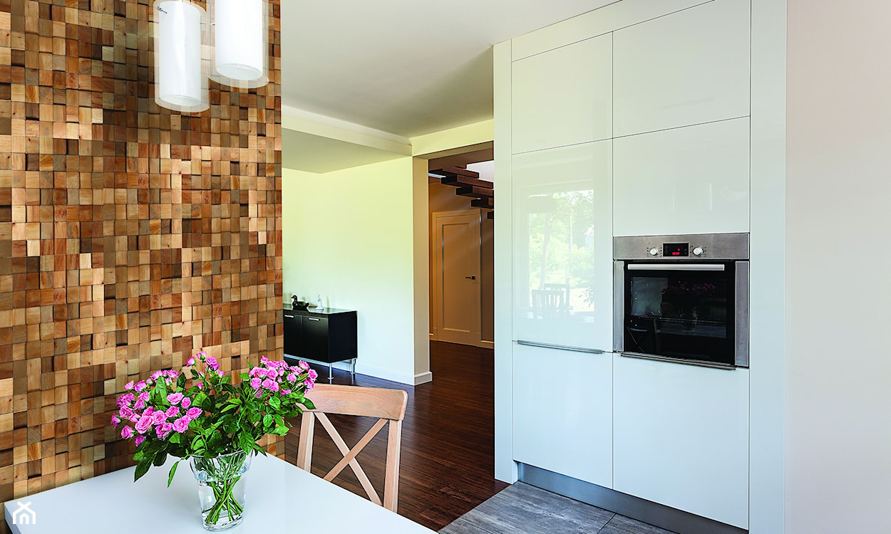drewniane panele na ścianie w kuchni, biały stół, białe meble kuchenne z połyskiem