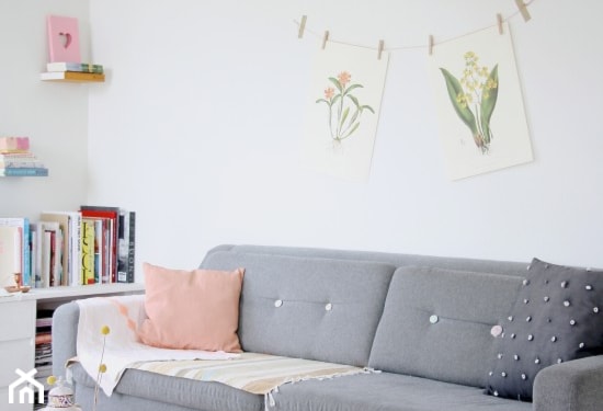 szara sofa, różowa poduszka, biała szafka z ksiązkami