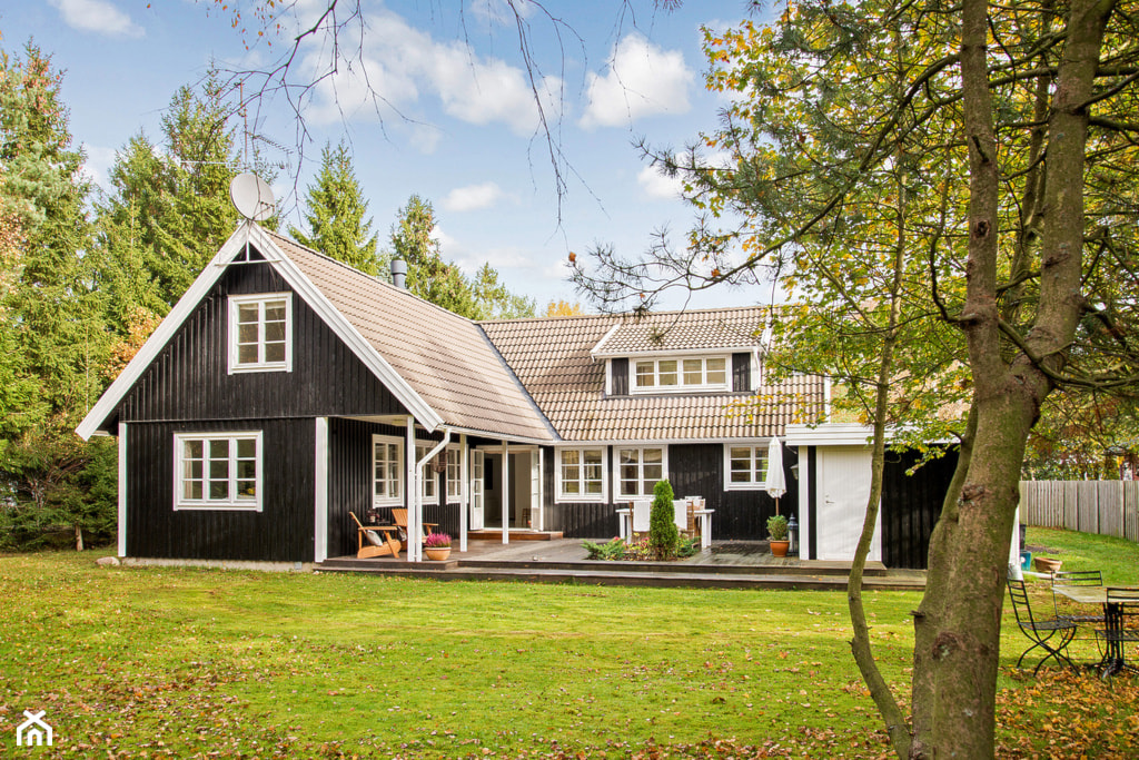 dom z drewna w ciemnym kolorze z białymi wykończeniami styl skandynawski