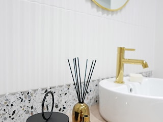 mała łazienka z wanną ze złotymi dodatkami