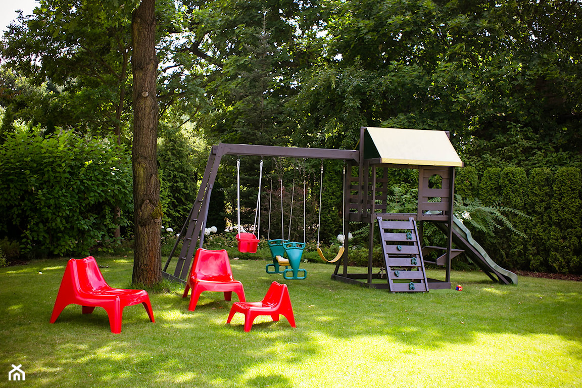 drewniana huśtawka, plastikowe fotele w ogrodzie, drewniany domek dla dzieci