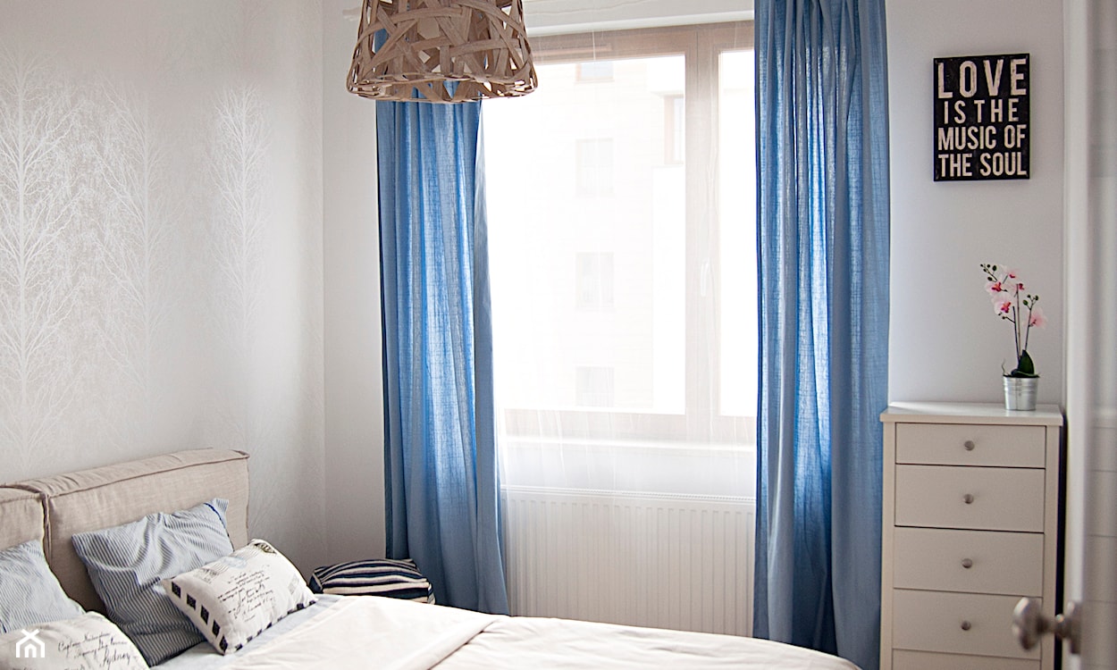 niebieskie zasłony w sypialni, lampa wisząca z plecionym abażurem, biała komoda