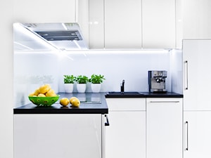 czarno - biała kawalerka - Mała otwarta biała z zabudowaną lodówką z nablatowym zlewozmywakiem kuchnia w kształcie litery l, styl minimalistyczny - zdjęcie od nomad studio