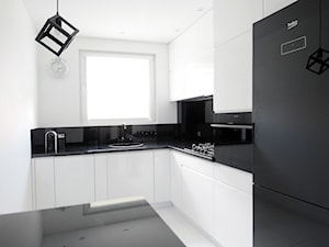 Biało-czarna kuchnia - Średnia zamknięta z kamiennym blatem biała z zabudowaną lodówką z nablatowym zlewozmywakiem kuchnia w kształcie litery l z wyspą lub półwyspem z oknem z kompozytem na ścianie nad blatem kuchennym, styl nowoczesny - zdjęcie od FORMA-MEBLE.PL