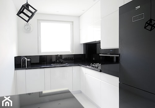 Biało-czarna kuchnia - Średnia zamknięta z kamiennym blatem biała z zabudowaną lodówką z nablatowym zlewozmywakiem kuchnia w kształcie litery l z wyspą lub półwyspem z oknem z kompozytem na ścianie nad blatem kuchennym, styl nowoczesny - zdjęcie od FORMA-MEBLE.PL