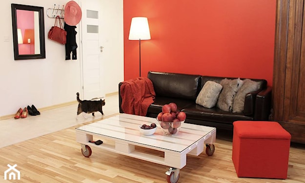 biały stolik z palet na kółkach, czerwona ściana, biała ściana, drewniana podłoga