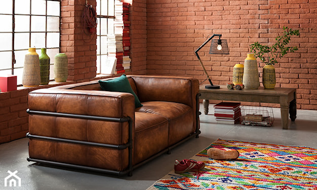 skórzana sofa i wzorzysty dywanik w industrialnym wnętrzu